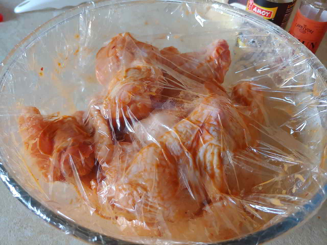 Chicken wings marinated in wet mix and covered in cling film