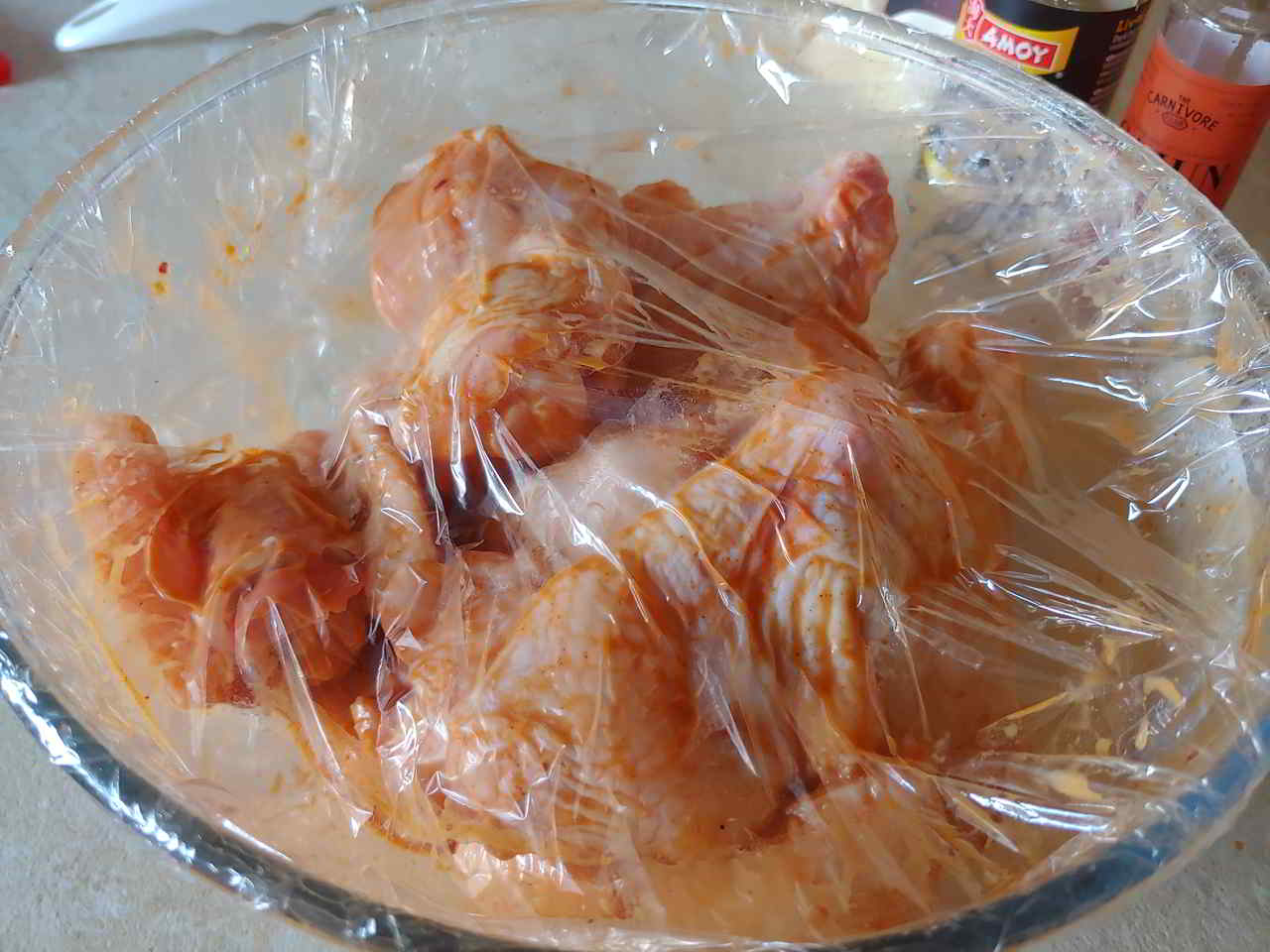 Chicken wings marinated in wet mix and covered in cling film