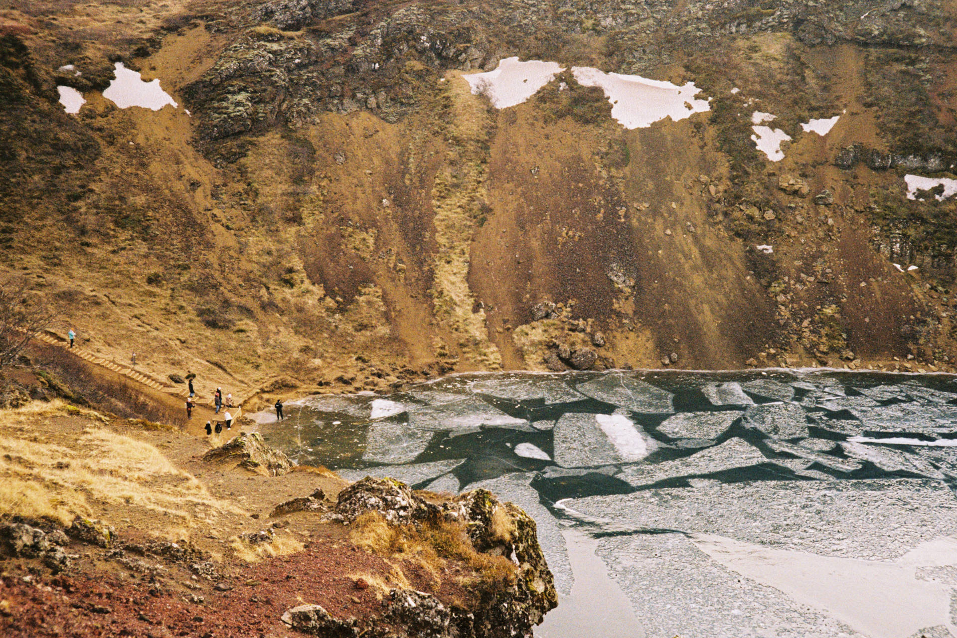 A photograph of a dormant volcanic crater covered in a layer of ice