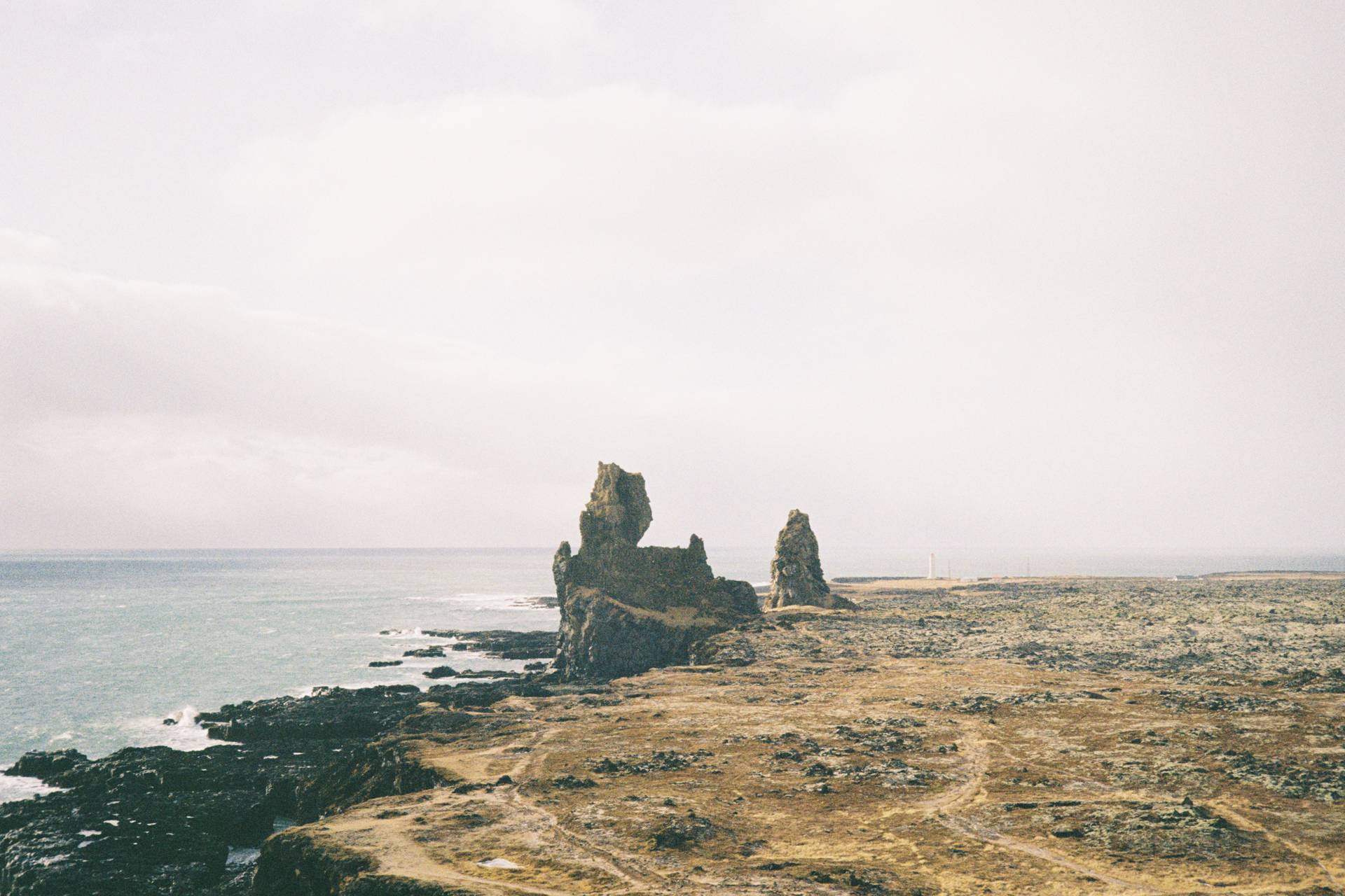 A photograph of two rocks (known as trolls) on a cliff by the shore